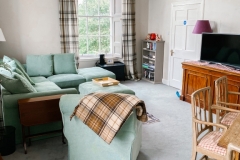John McDouall Stuart View - Living room with four seater corner couch, TV and dining table